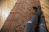 Antique Kurdish runner featuring geometric stepped medallions in red orange and camel tones, showing mostly even wear.
