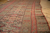 Antique Kurdish runner with geometric stepped diamond patterns, worn pile, red-orange, camel, ivory.
