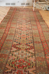 Antique Kurdish runner's geometric medallions in red-orange, camel, and ivory, showing mostly even wear.