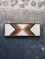 Rectangular geometric wood art featuring distressed white, natural, and dark tones with brass.