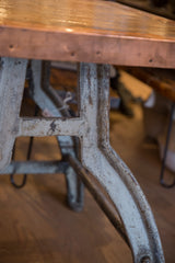 Distressed antique industrial bronze table base with worn finish and copper edge.