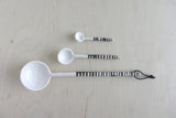 Three handmade white ceramic spoons with black striped handles, large 11-inch spoon with loop.