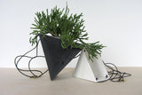 Black and white porcelain triangle planters, with green plant and hanging cords.