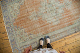 Distressed vintage Oushak rug pile revealing knot heads and foundation, with peach, ivory, blue tones.
