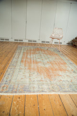 Evenly distressed vintage Oushak carpet, blending blush peach and pale blue tones.
