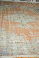 Distressed vintage Oushak rug pile showing blush peach, ivory, and faint blue tones.