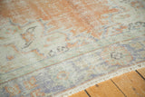 Distressed Oushak carpet texture with exposed knot heads, blush peach, ivory, and pale blue.