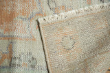 Hand-knotted distressed pile, visible woven foundation, and end fringe.