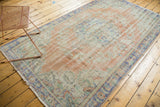 Distressed Oushak carpet corner with blush rose peach, ivory, and pale blue border.