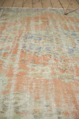 Close-up of distressed vintage Oushak carpet pile, showing knot heads, blush peach, and ivory tones.