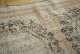 Distressed Oushak rug pile with visible knot heads and foundation in blush, charcoal, and ivory.