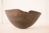 Textured dark wood vintage African bowl with distinct cracks and a chipped rim.