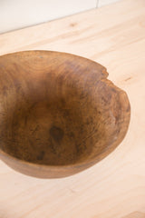 Vintage wooden African bowl with textured interior and prominently chipped rim.