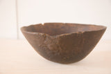 Dark brown vintage African bowl showing hand-carved texture and irregular rim.