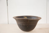 Primitive hand-carved dark wood African bowl showing aged cracks and metal repair.