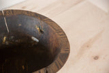 Vintage African wooden bowl showing cracks, metal repairs, and carved rim details.