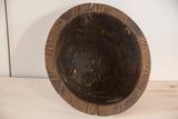 Dark, hand-carved interior of a primitive African wooden bowl, showing cracks and repairs.
