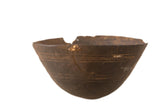 Vintage hand-carved African wooden bowl with deep brown tones, visible cracks, and gold-tone repairs.