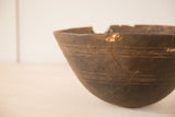 Close-up of dark vintage African wooden bowl rim with cracks and visible repairs.