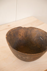 Primitive dark wood surface with carved texture and irregular top rim of the African bowl.