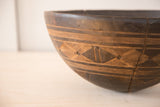 Close-up of hand-carved primitive African wooden bowl with geometric patterns and crack.