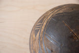Dark textured wood of vintage African bowl, with carved patterns and visible crack repair.