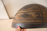 Vintage hand-carved African wooden bowl with geometric pattern and visible crack.