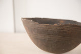 Dark hand-carved texture and primitive chipped rim of vintage African bowl.