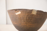 Cracked vintage wooden African bowl with metal and paper repairs, hand-carved texture.