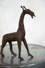 Vintage African giraffe sculpture in profile, showing its rustic copper finish and carved details.