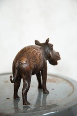 Copper hippo sculpture, back view, showcasing its curled tail and warm patina.