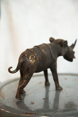 Rear view of vintage African copper rhino sculpture, highlighting its curled tail and aged patina.