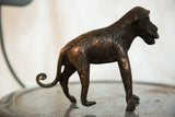 Vintage African copper monkey sculpture, side view with textured body and coiled tail.