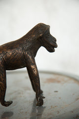 Vintage African copper monkey sculpture with a textured profile of its head.