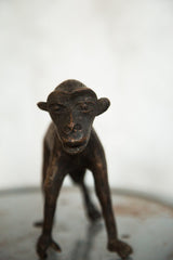 Close-up of vintage African copper monkey sculpture, highlighting the detailed face and dark patina.