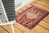 Small antique Serapi rug with authentic wear and asymmetric motifs styled on a wood floor.