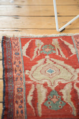 Corner view of an antique Serapi rug showing its tattered end loss and wear to the knot heads.