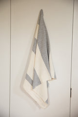 Draped hand-woven cotton throw with wide cream and light gray stripes.