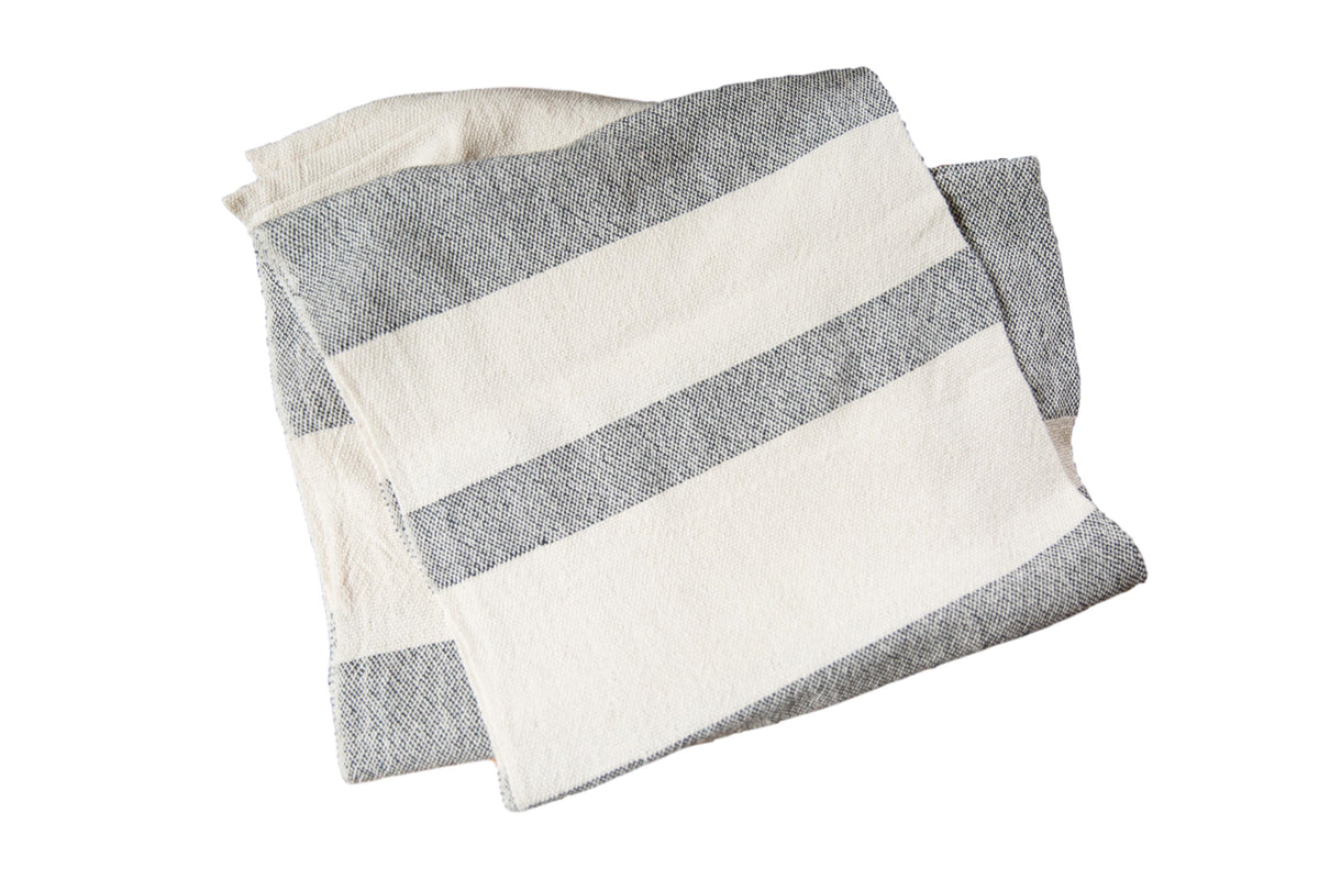 Hand-woven cotton spa towel with bold black and cream ticking stripes shown folded.