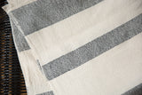 The textured weave of a hand-woven cotton throw with black and cream ticking stripes.