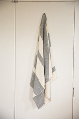 Hand-woven cotton throw with cream and black ticking stripes, hanging to show its natural drape.