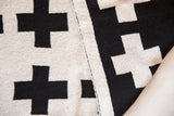 Reversible Swiss cross blanket folded to show black and off-white knit patterns.