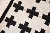 Black Swiss cross pattern, woven texture, and border detail on the cream baby blanket.