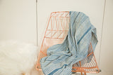 Draped hand-woven indigo striped African textile showing varied blue hues and supple texture.
