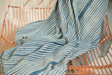 Draped blue and white striped African indigo textile, revealing supple handwoven texture.