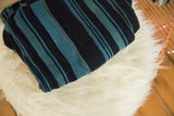 Folded vintage African indigo textile with hand-woven texture and varied blue stripes.