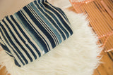 Folded vintage African indigo textile, highlighting handwoven texture and varied striped patterns.
