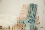 Denim Mossi Indigo African textile throw draped over a chair, featuring hand-dyed texture and fringe.