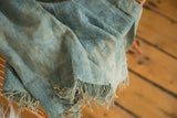 Vintage denim indigo textile with handwoven texture and raw fringed edge.