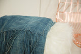 Folded vintage indigo African textile throw, showing hand-woven cotton texture and fringed detail.